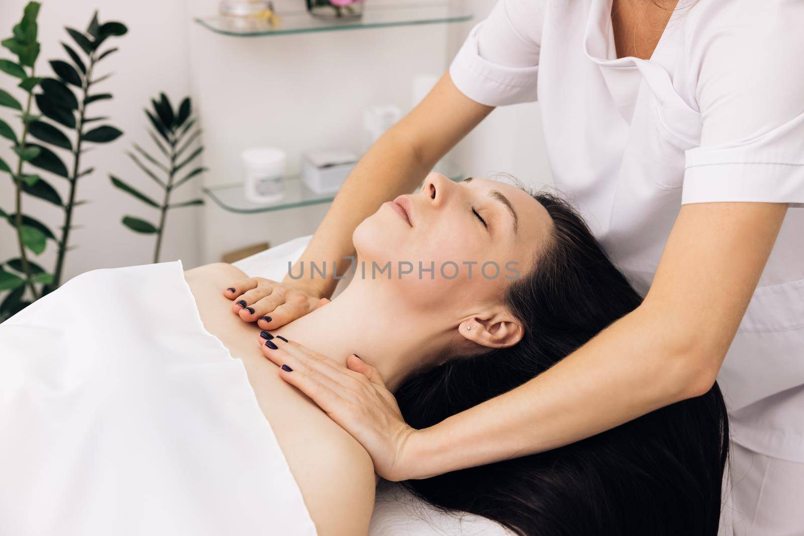 Cosmetologist is touching girl's face. Facial cleansing with professional cosmetic facial massage. Woman is having cosmetic treatment at spa salon by uflypro