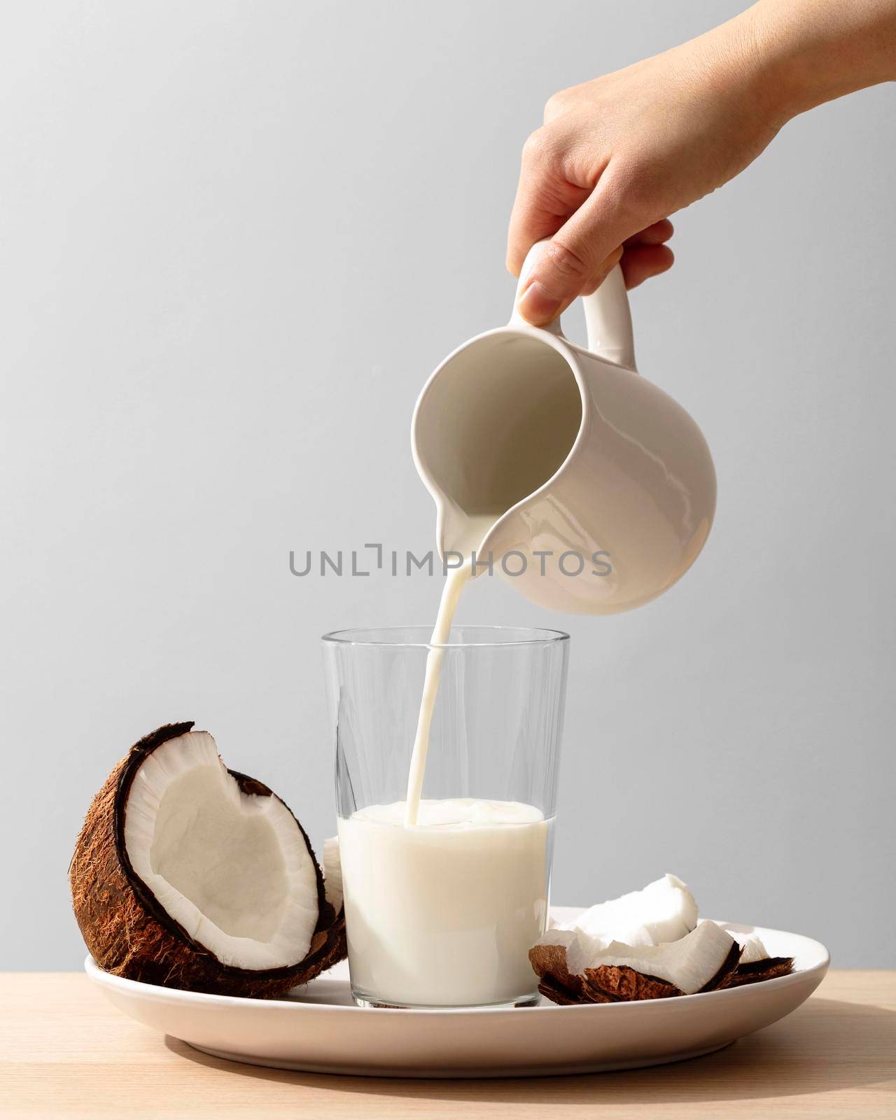 front view hand pouring coconut milk glass. High resolution photo