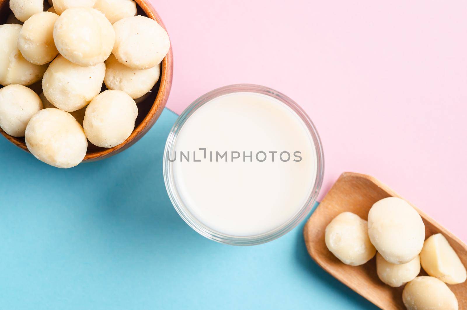 Macadamia milk in a glass and a bowl of macadamia nuts on beautiful background.