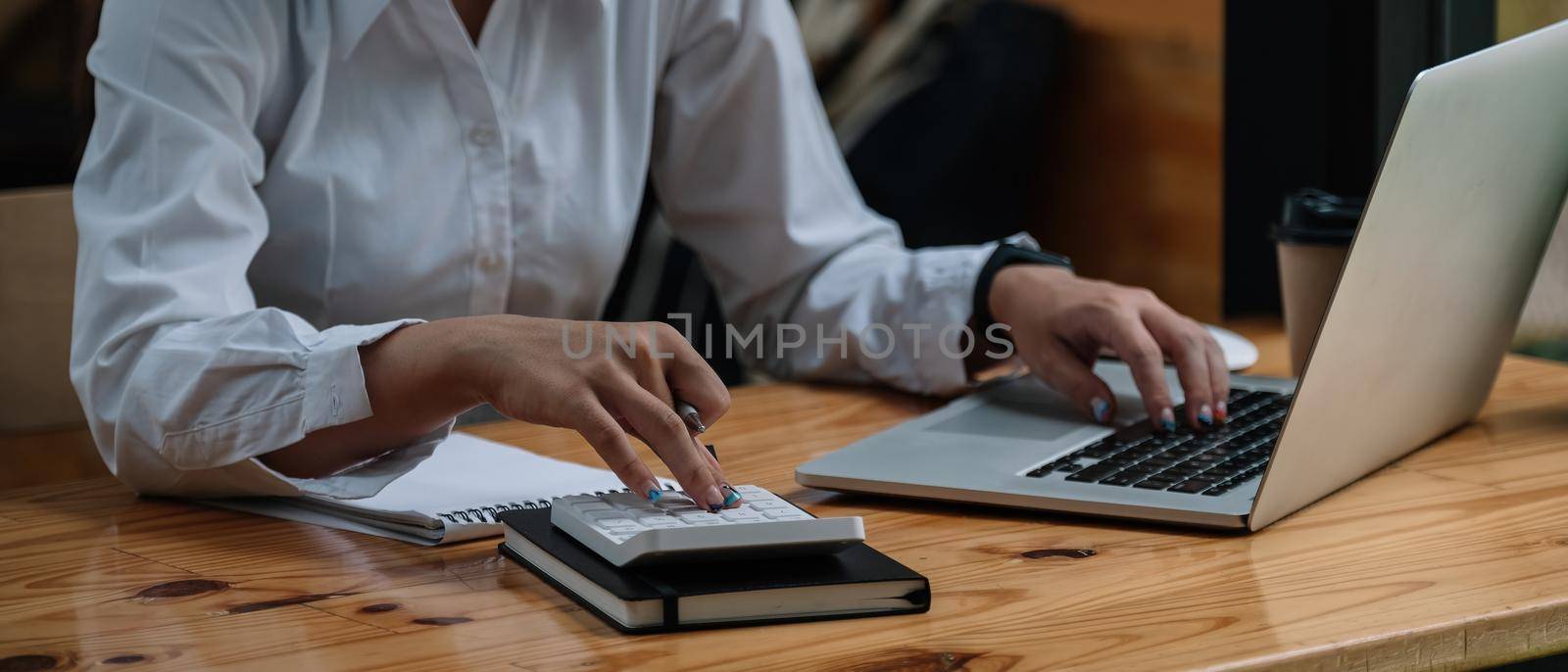 Close up accountant woman working about financial and analysis business document with calculator and holding glasses at his office to calculating expenses, Accounting concept