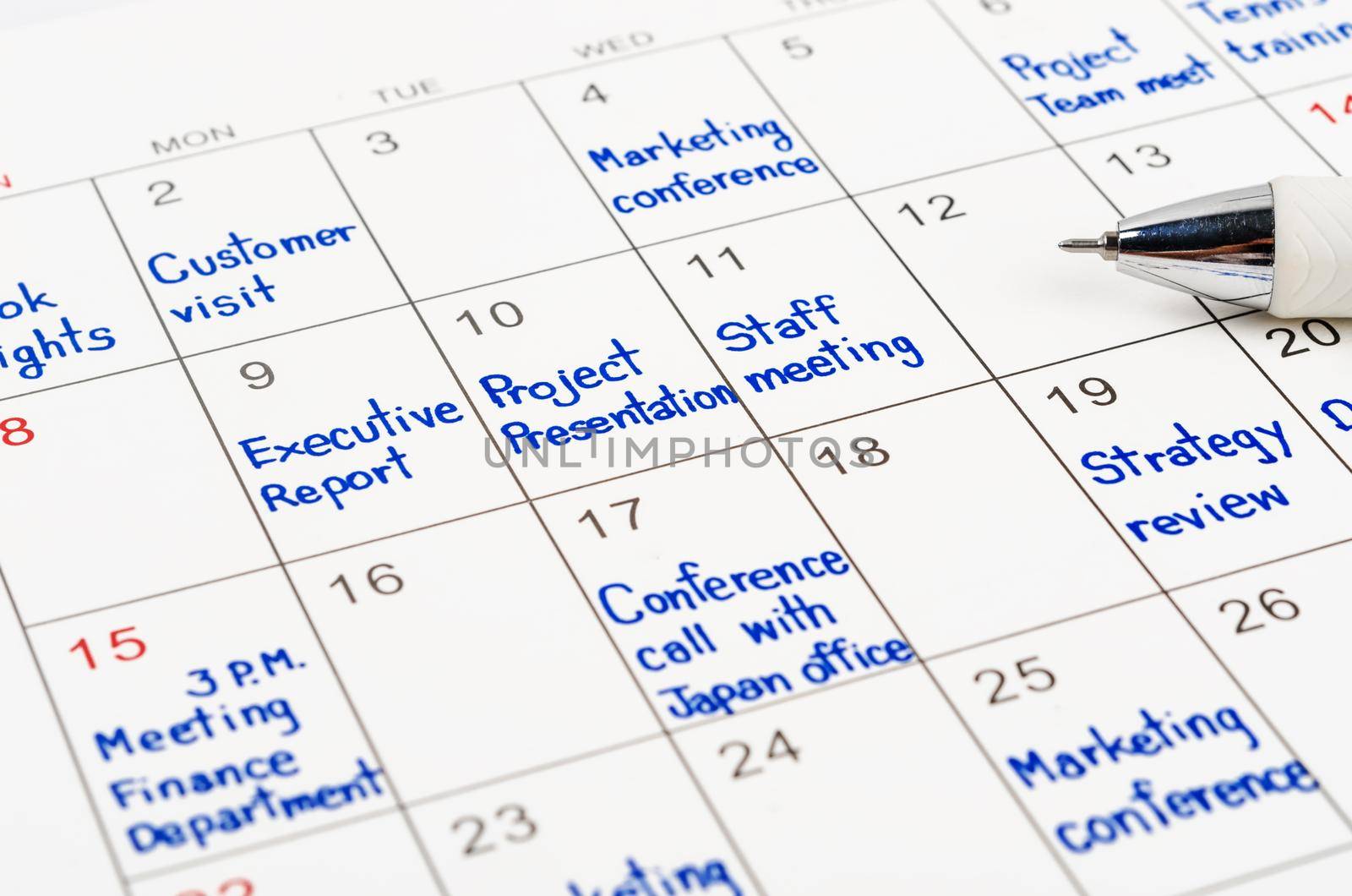 Handwriting scheduling appointments on calendar sheet with pen.