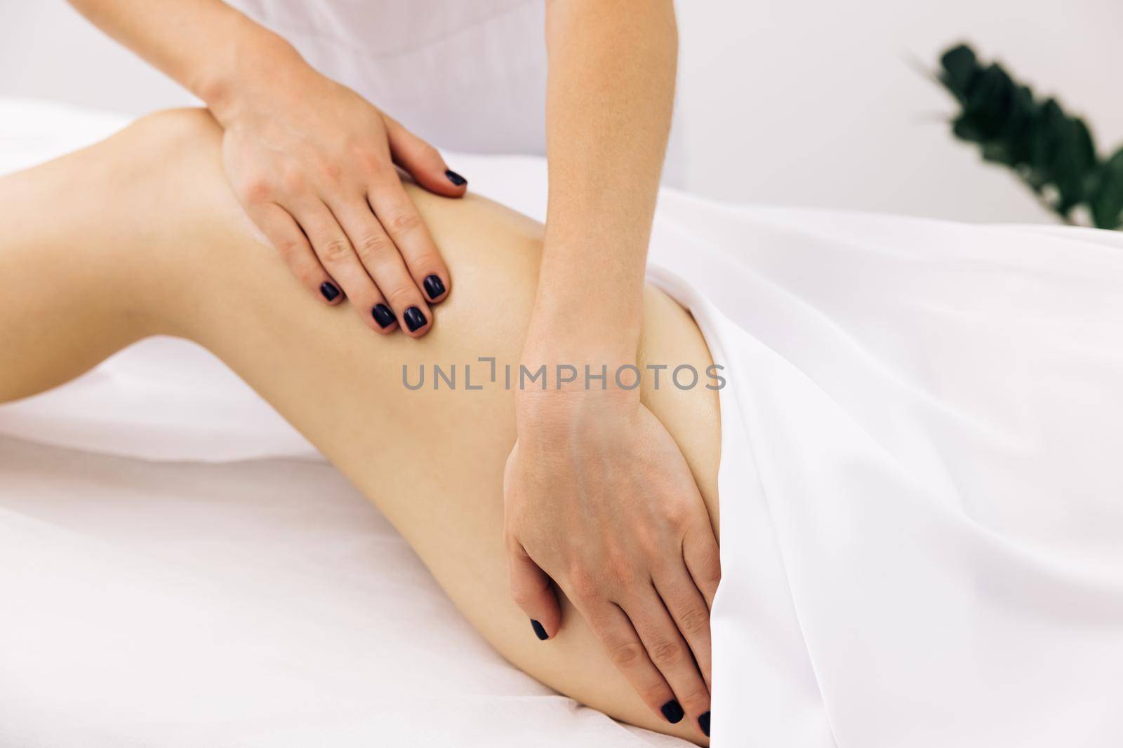 Close up Therapeutic massage of the female leg. Female hands doing professional massage to a woman on a massage table. Beauty treatments by uflypro