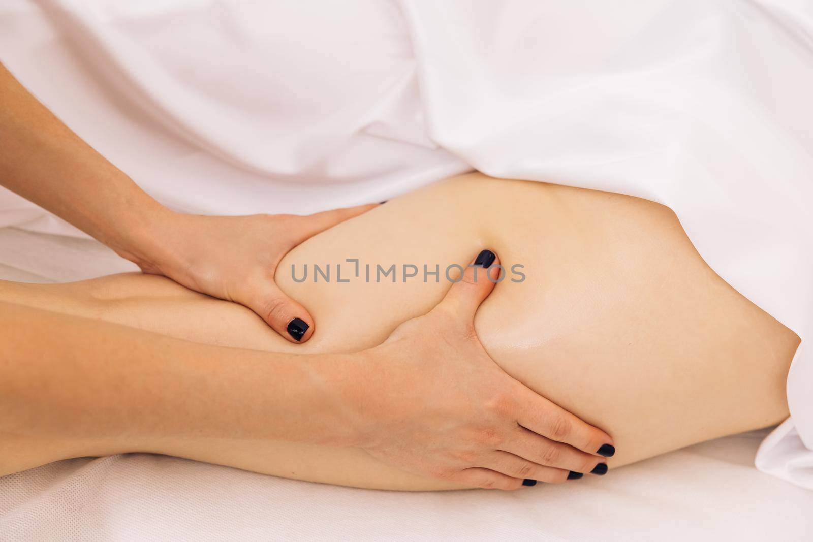 Close-up Master masseur performs anti-cellulite massage for girl. Procedure of manual anti-cellulite massage of the female hip in the beauty studio by uflypro