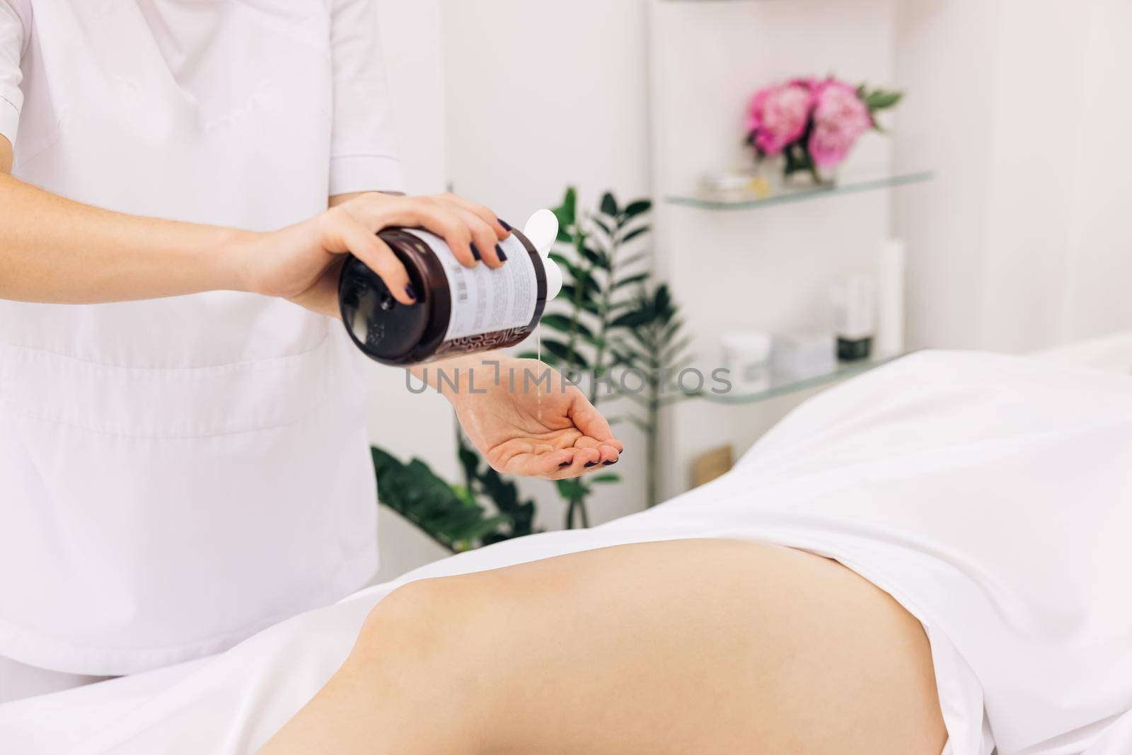 Therapeutic massage of the female leg. Woman hands doing professional massage. Creme treatment on woman legs with hydrating lotion. Preventing dry skin on female body parts close-up.