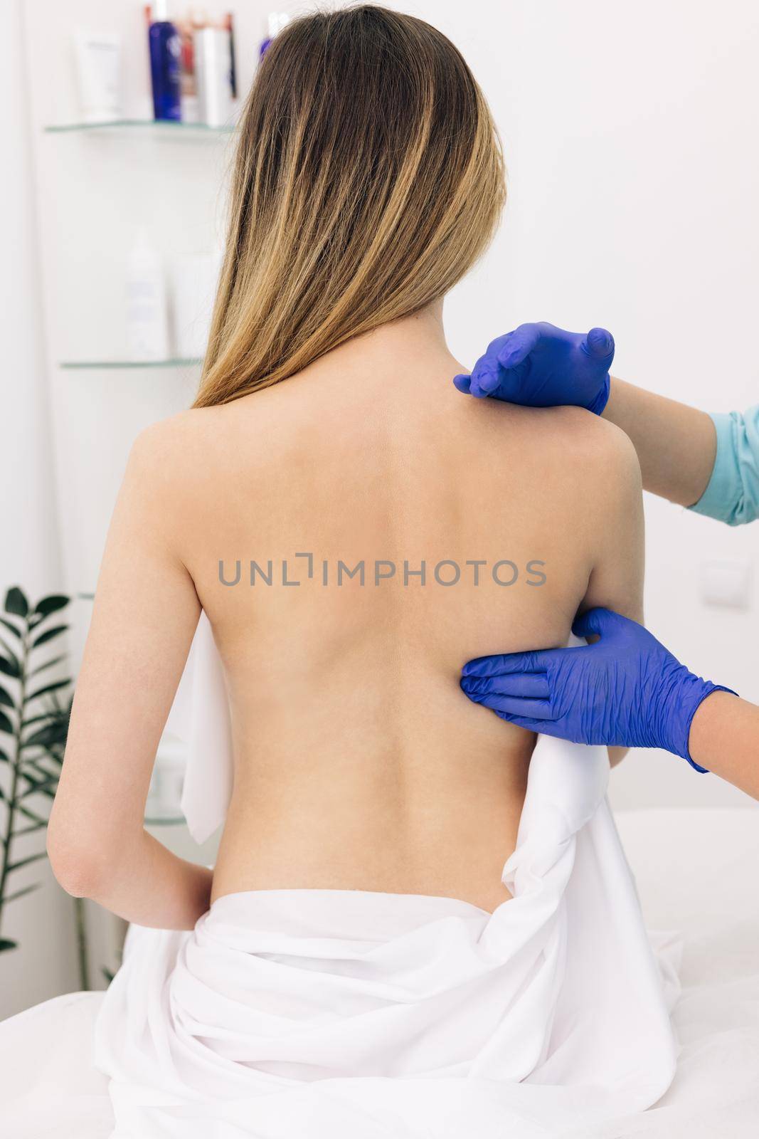 Female patient sitting in modern rehab center while woman physiotherapist helping him rasing his arm. Physiotherapist worker doing treatment to his client.