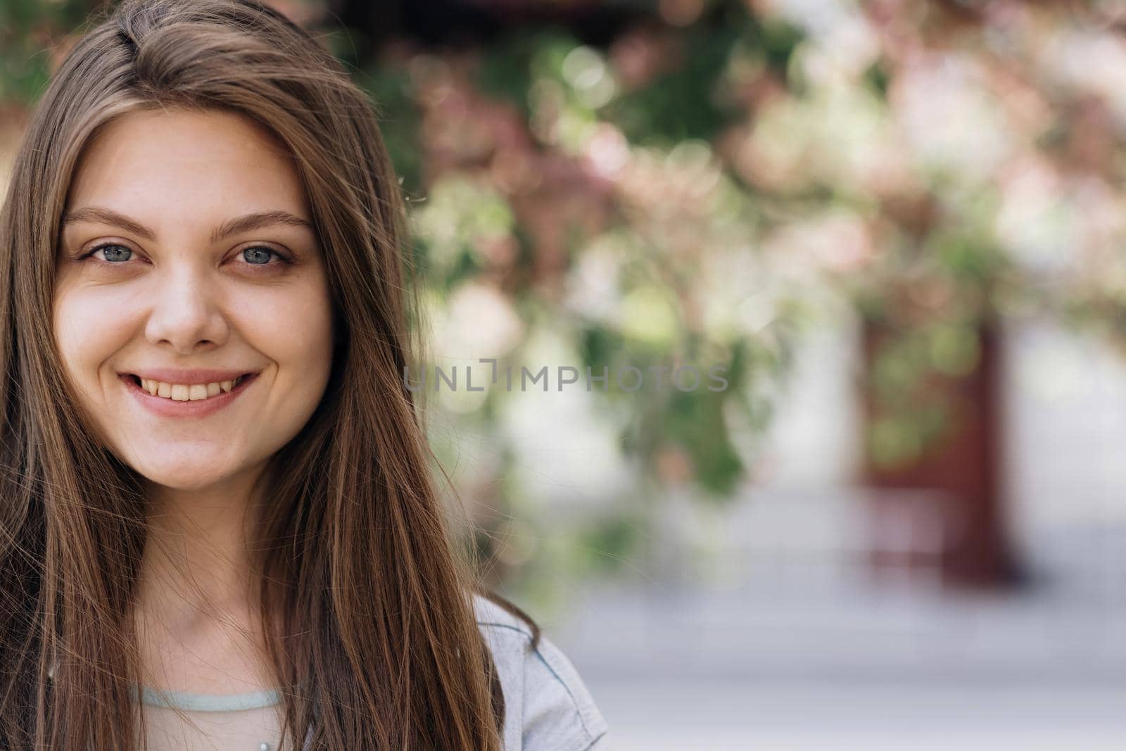 Beautiful face of tender attractive woman staying outside. Attractive young lady with her hair blowing in the wind. Perfect model with creative vivid makeup and pink lipstick on lips. Ethnicity by uflypro