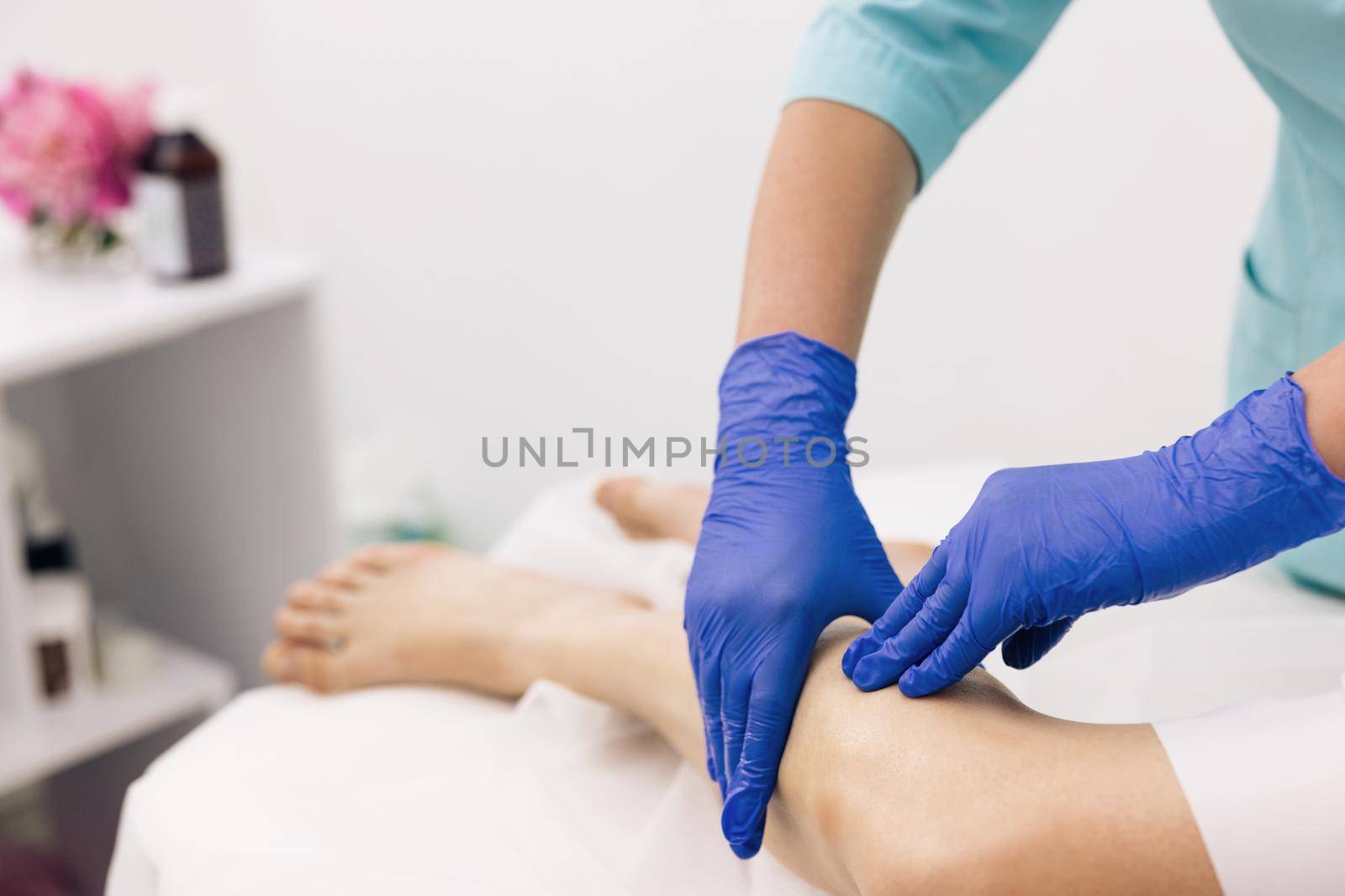 Physiotherapist worker woman assisting physical medical exercise recovery after injuries. Doctor in gloves examining painful knee of female patient leg trauma. Healthcare medical insurance concept.