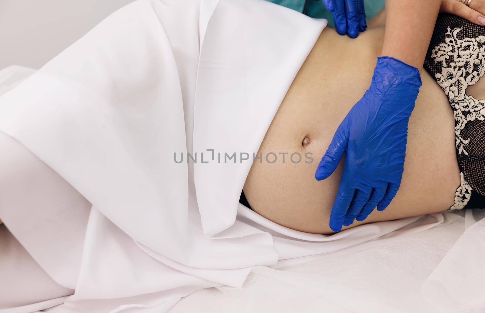 Physiotherapist woman massaging tummy on pregnant woman on a stretcher. Pregnant woman visit gynecologist doctor at hospital or medical clinic for pregnancy consultant. Gynecology concept