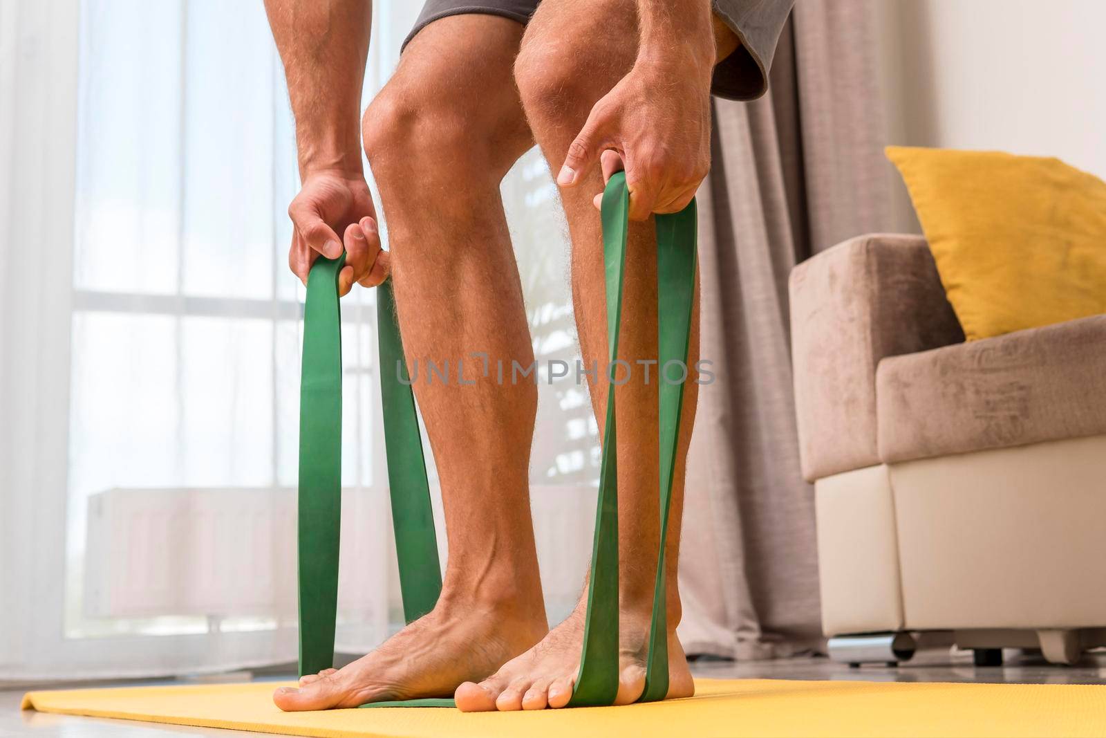 man working out home using elastic band. High quality photo by Zahard