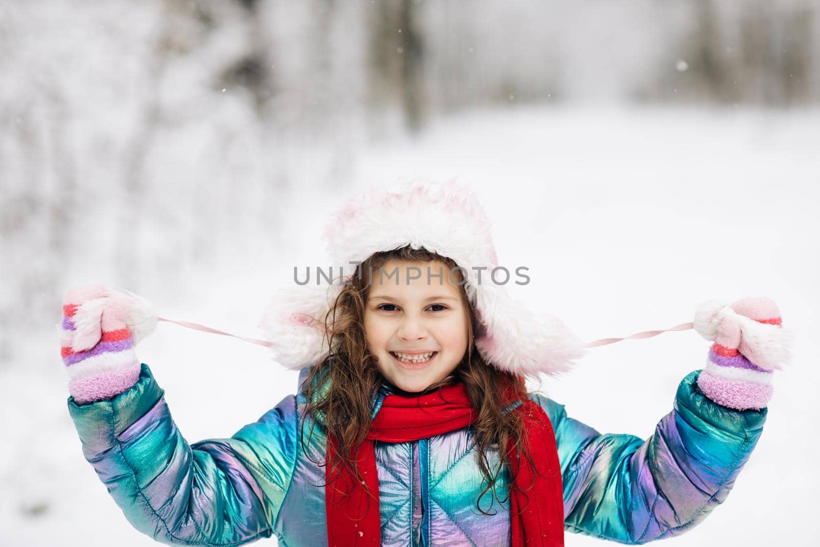 Happy child girl plays with a snow in winter day. Girl enjoys winter, frosty day. Playing with snow on winter holidays. Walk in winter forest.