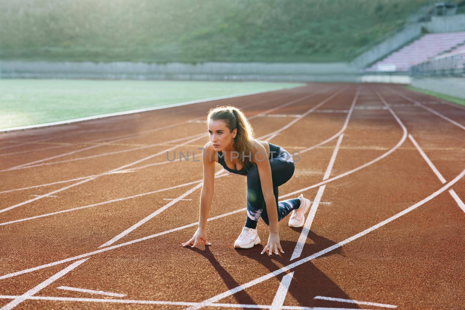 Young Athlete Woman Running Fast at Track in the Morning Light , Training Hard, Getting Ready for Race Competition or Marathon. Fit Girl in Black Sportswear Jogging on a Running Track.