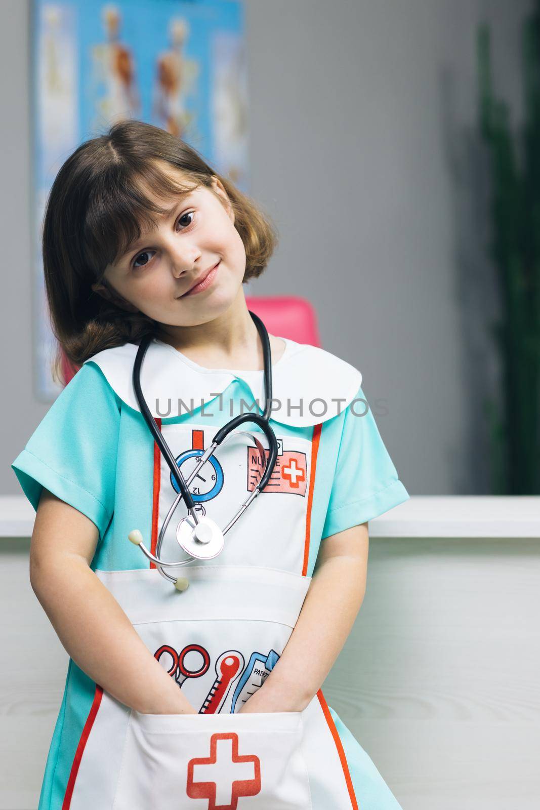 Funny little girl looking at camera at home. Cute kid child with pretty face. Concept of a happy childhood. Portrait of girl in medic uniform looking at camera