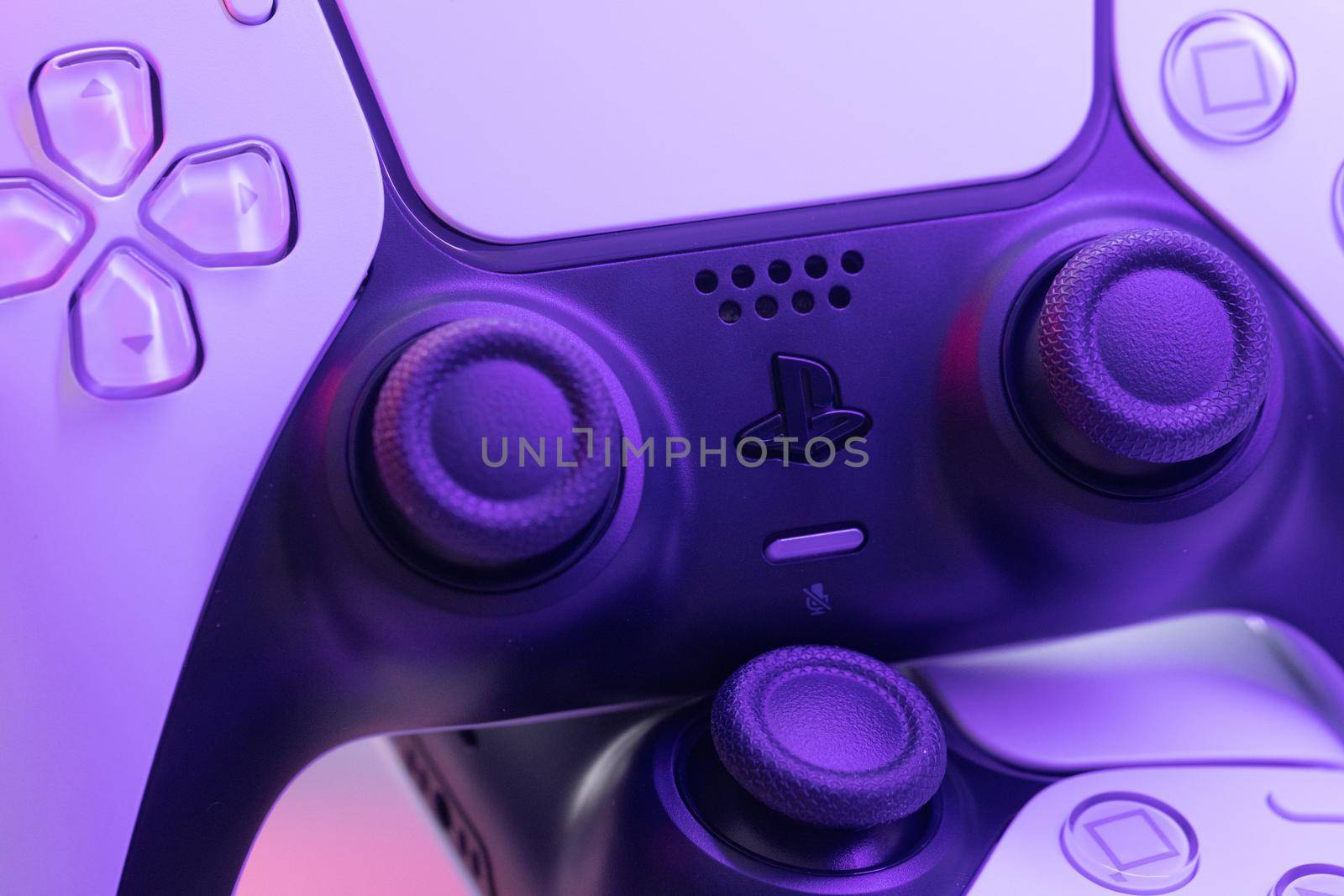 Lviv, Ukraine - February 27 2021: Two joysticks from Sony PlayStation 5 TV game console on a white background. Close up view of 2 controllers from new console with light. by uflypro