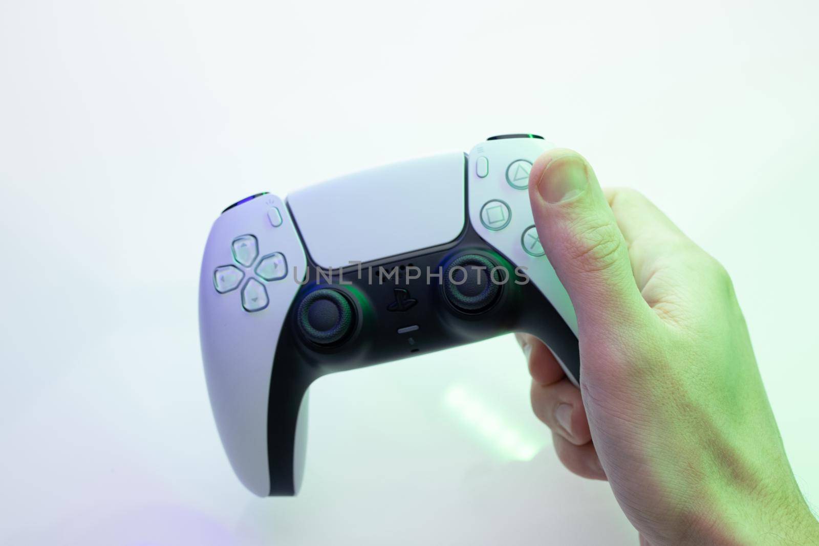 Lviv, Ukraine - 27 February 2021: Player is holding controller of new PlayStation 5 game console. Man presses buttons on game joystick and play game by uflypro