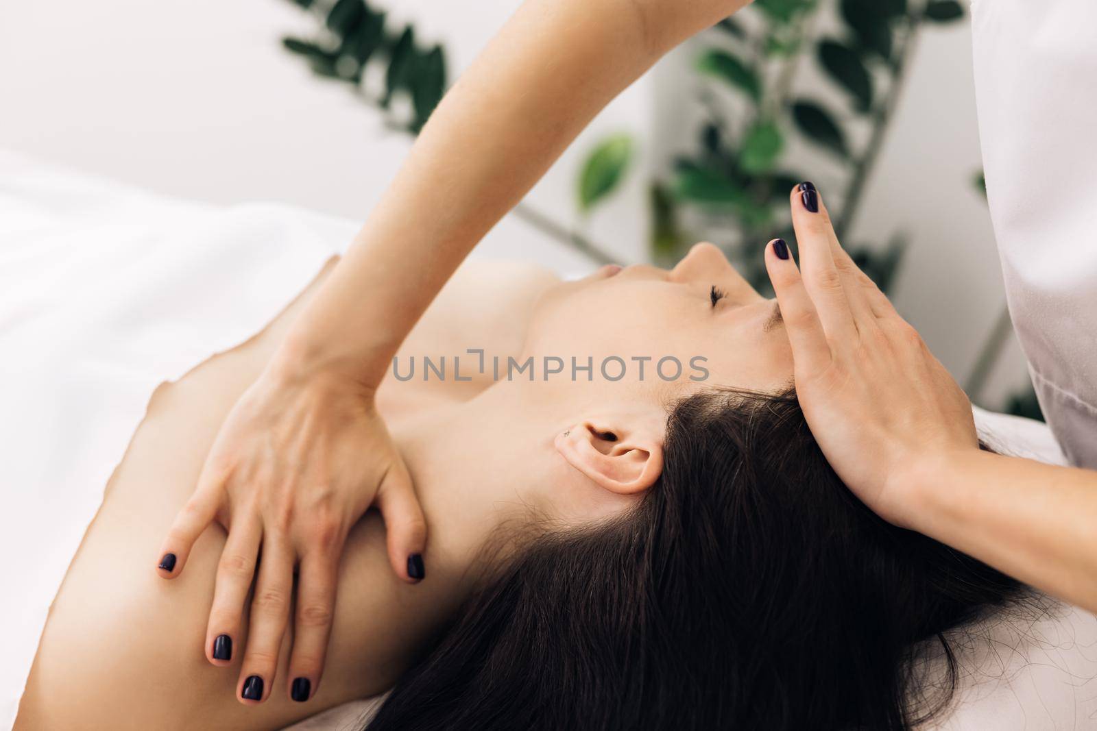 Woman is having cosmetic treatment at spa salon. Cosmetologist is touching girl's face. Facial cleansing with professional cosmetic facial massage