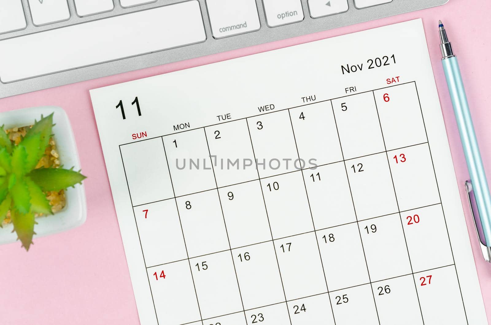 November 2021 calendar sheet with keyboard computer on pink background.