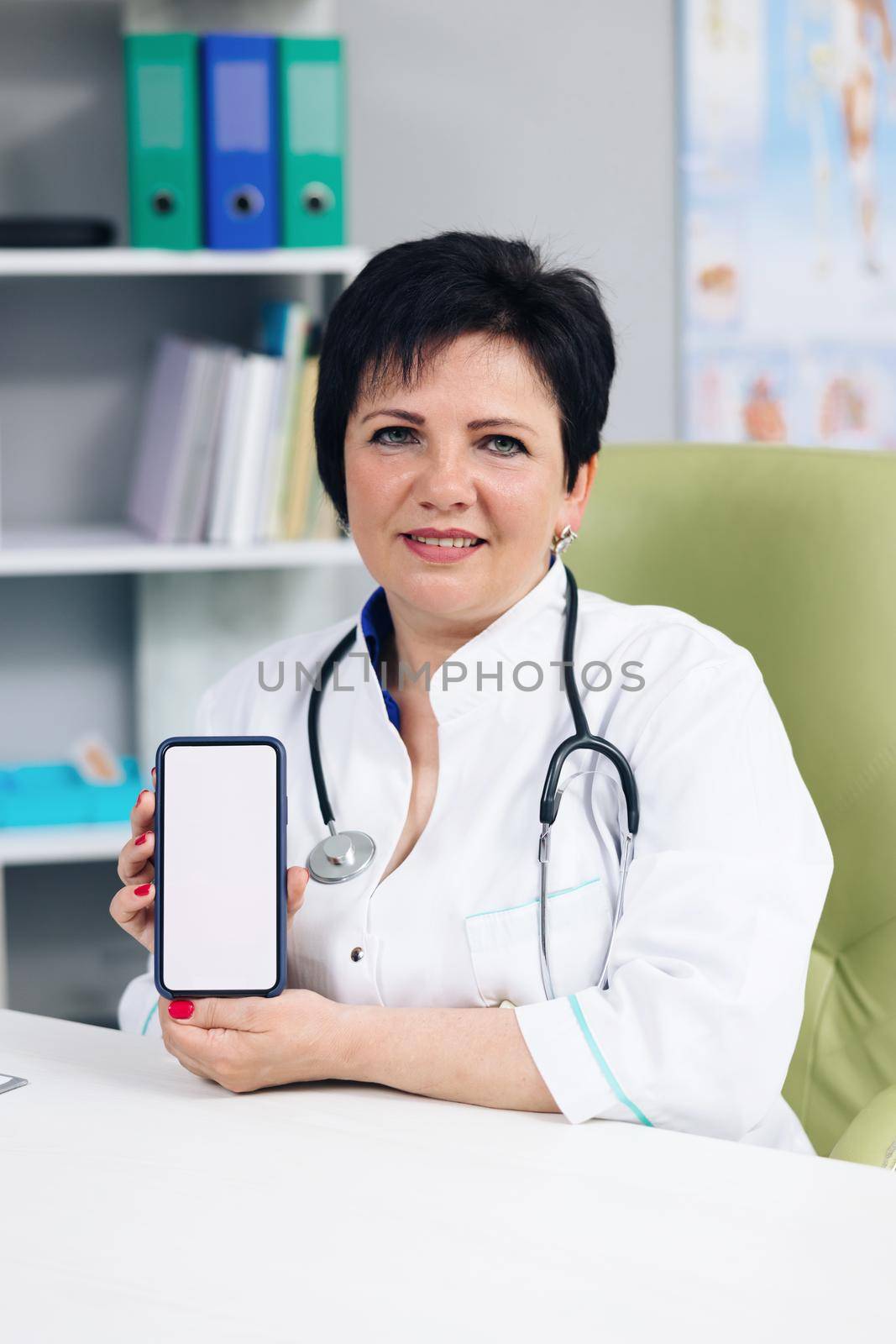 Vertical Photo Medical Doctor Showing Test Results to a Patient on a Smartphone with White Screen in a Health Clinic. Physician is Making Conference Video Call by uflypro