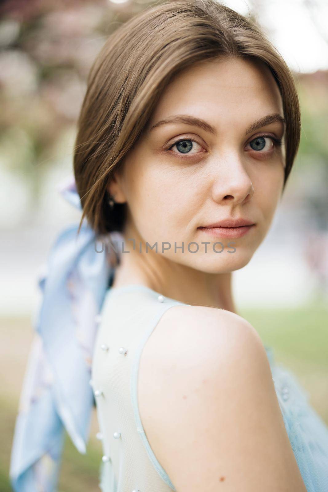 Vertical format Face of beautiful soft woman with natural make-up looking at camera. Portrait young pretty brunette girl outside at sunshine. Etnnicity. People. Beauty by uflypro