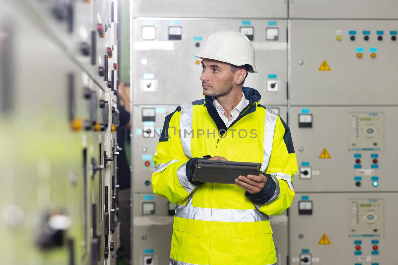 Technician inspect to control panel screen system for generate electricity of factory in manufacture industrial. Man electrical engineer hold tablet monitoring electrical system in control room by uflypro