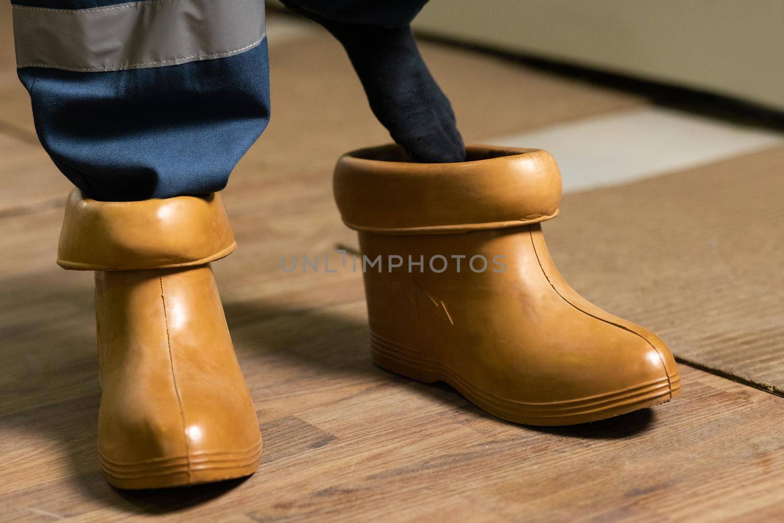 Electrician wears rubber boots. Electrical technician is putting on special protective shoes. High voltage power station. Concept of electric power station development by uflypro