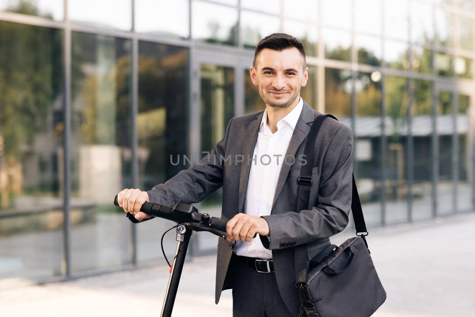 Portrait of confident businessman standing with electric scooter and looking at camera. Technology, business, Internet app concept. E-Scooter rider rent personal eco transport by uflypro