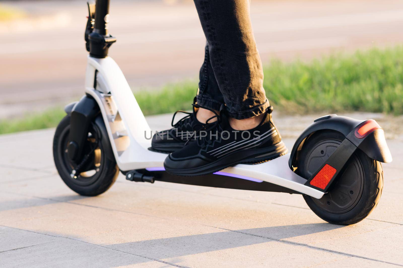Close up - Male riding electric scooter. Modern transportation gadget and popular futuristic device among young people. Attractive man stands, scoots and rides on the electric kick scooter. by uflypro
