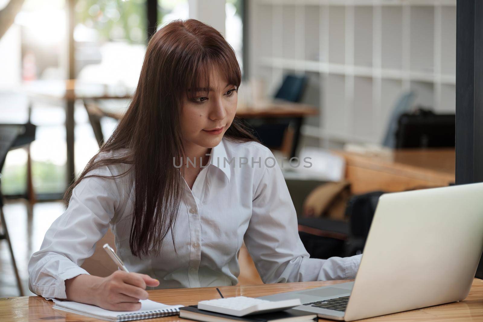Portrait of young asian woman writing making list taking notes in notepad working or learning on laptop indoors- educational course or training, seminar, education online concept