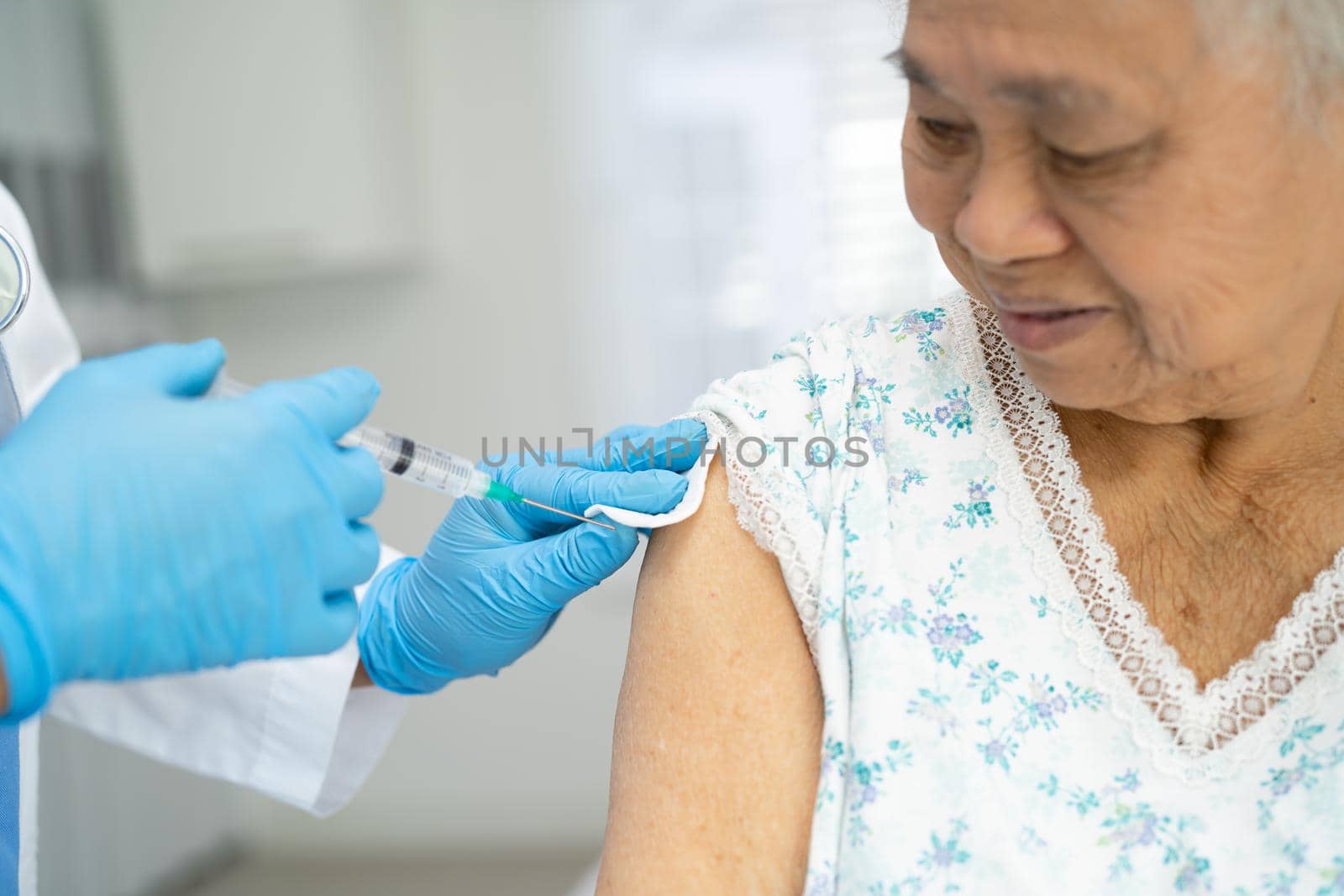 Elderly Asian senior woman wearing face mask getting covid-19 or coronavirus vaccine by doctor make injection.