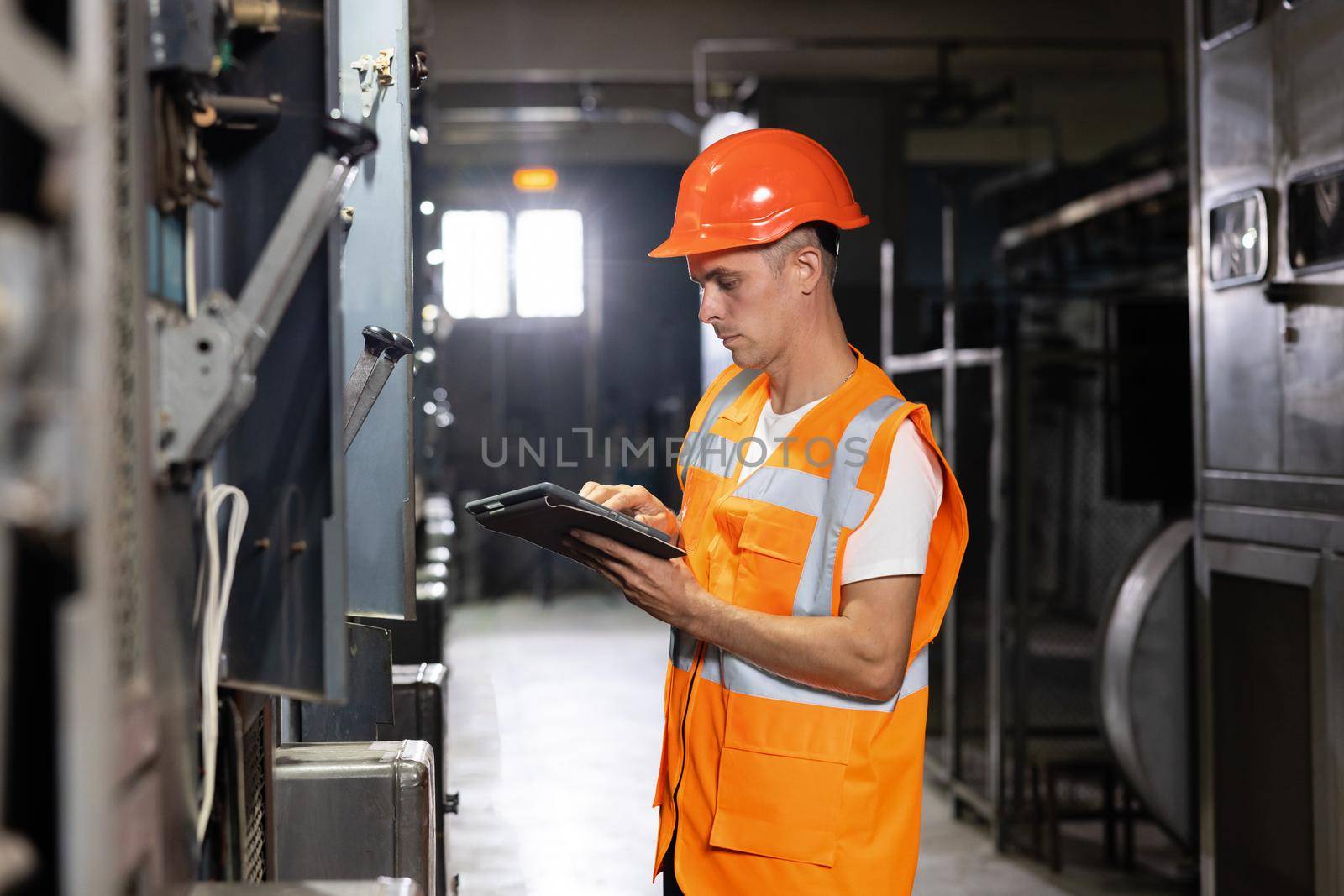 Engineer male working at factory. Electrical engineer using digital tablet inspect and program for electric power system in electrical control room. Concept of industry, factory, renewable energy by uflypro