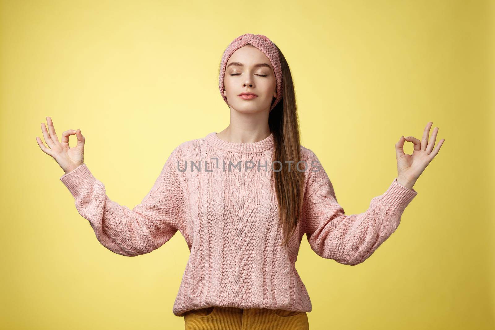 No stress. Pretty young female student not worry, releasing negative emotions during yoga training session standing in lotus pose, breathing smiling relieved happy, showing mudra sign feeling relaxed.