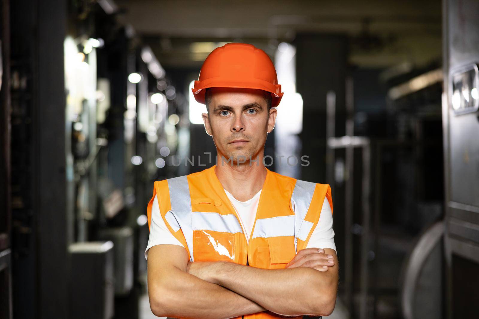 Portrait of an engineer man or worker crossing arms, working in electrical room station. Power energy motor machinery cabinets in control or server room, operator station network in industry factory by uflypro