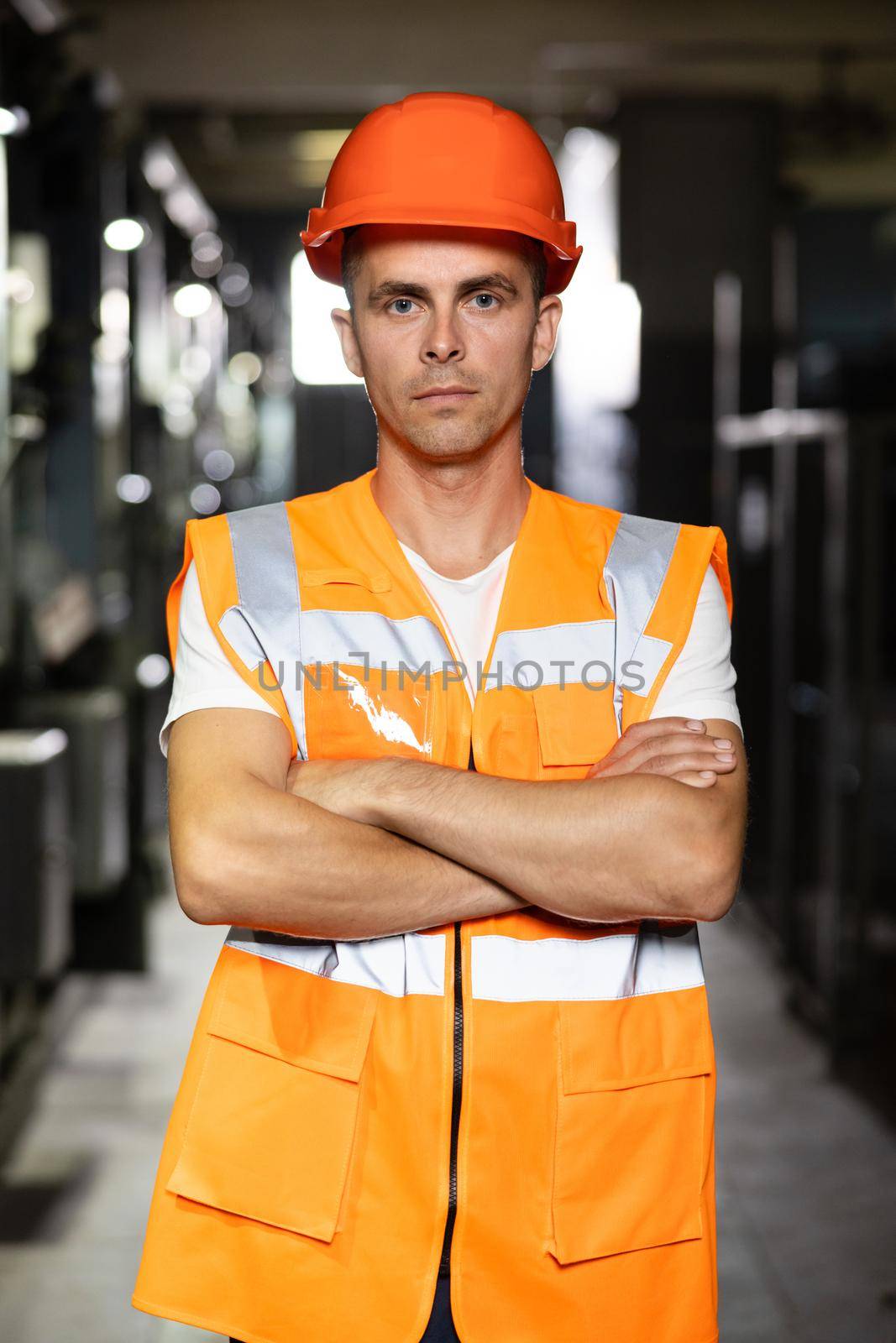Power energy motor machinery cabinets in control or server room, operator station network in industry factory. Portrait of an engineer man or worker crossing arms, working in electrical room station.