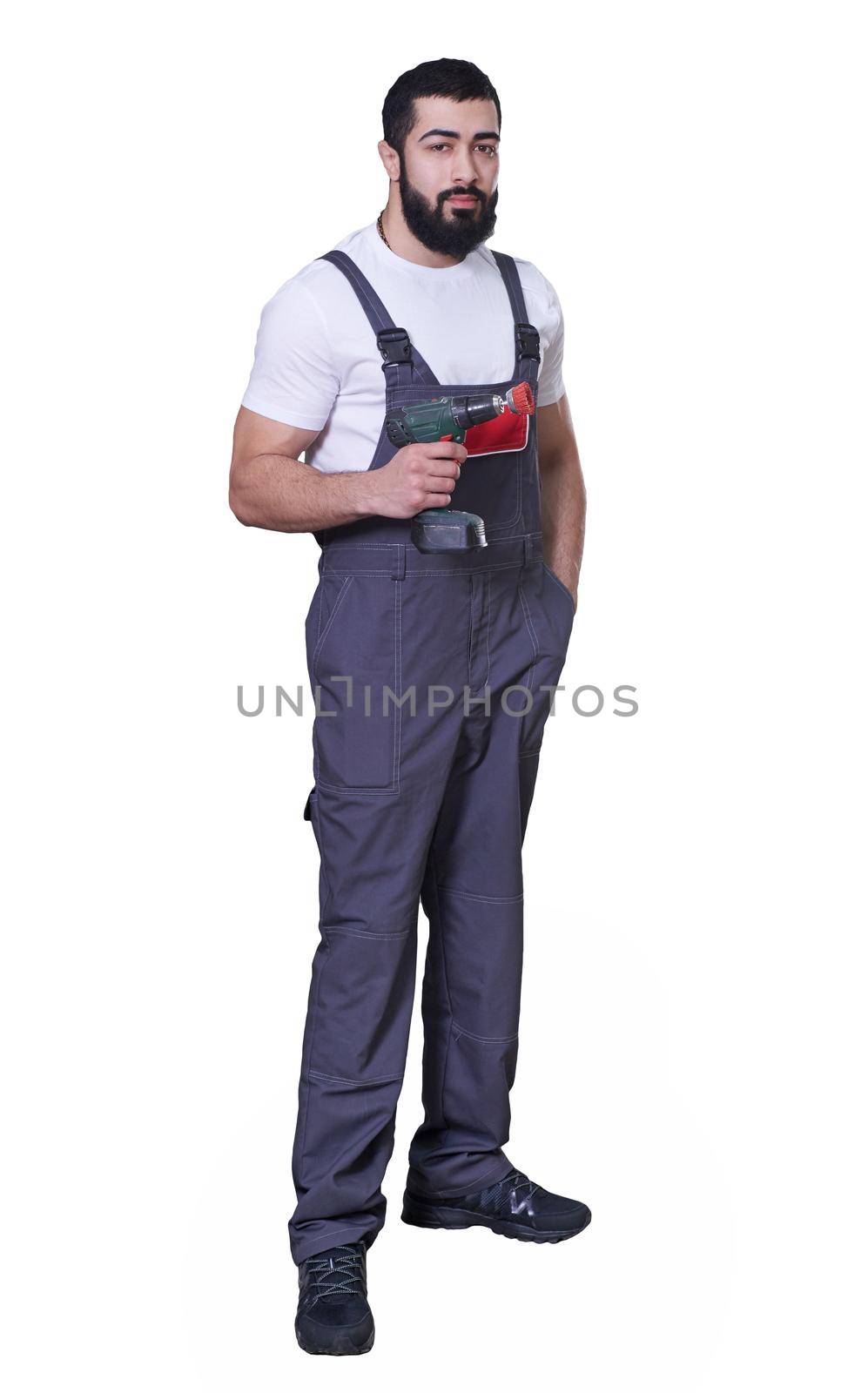 Worker wearing overalls standing and holding electric screwdriver or drill isolated on white background by Mariakray
