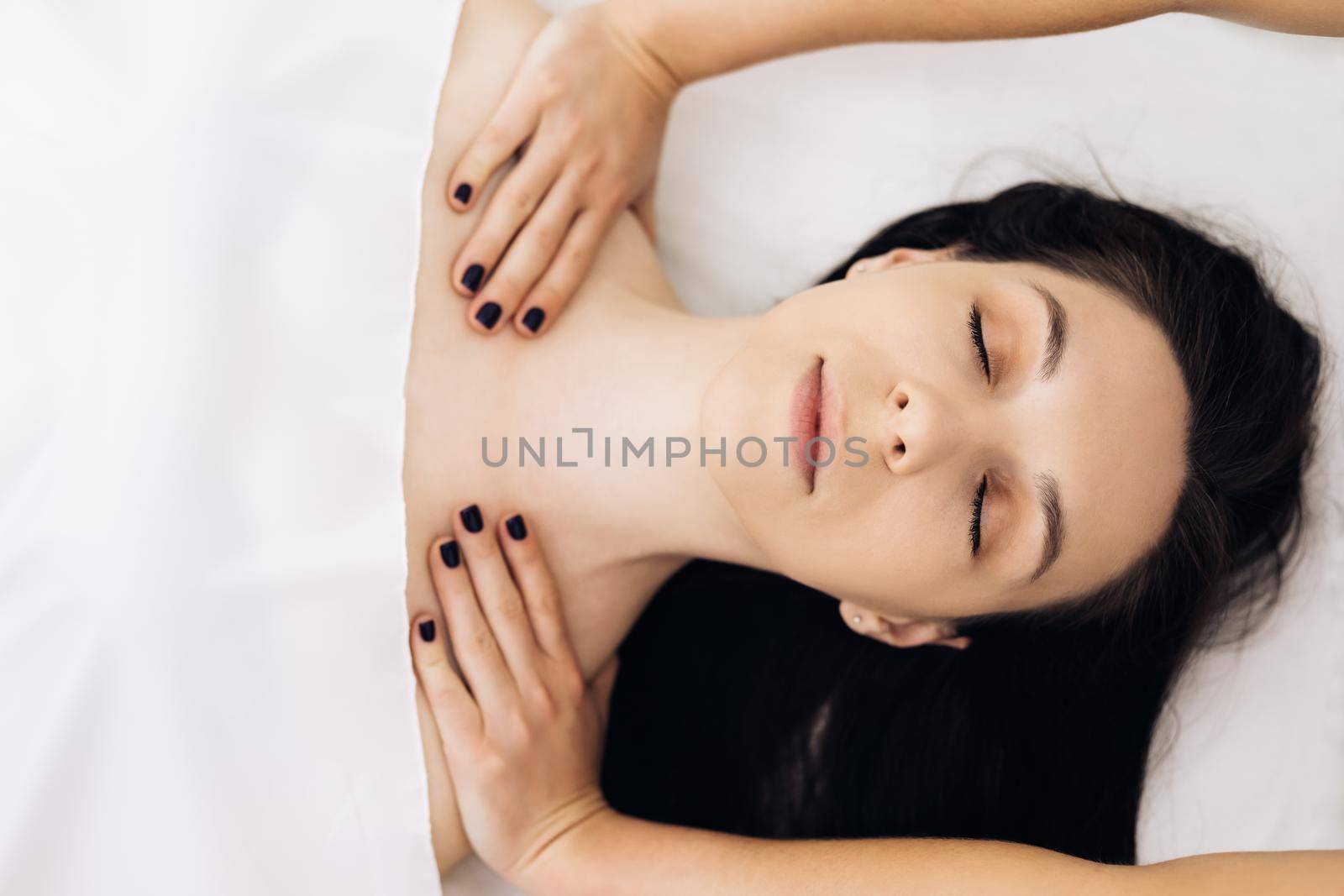 Top view of Young caucasian woman getting spa massage treatment at beauty spa salon. Face massage essential oil for skincare, Relaxing massage, Spa skin and body care.