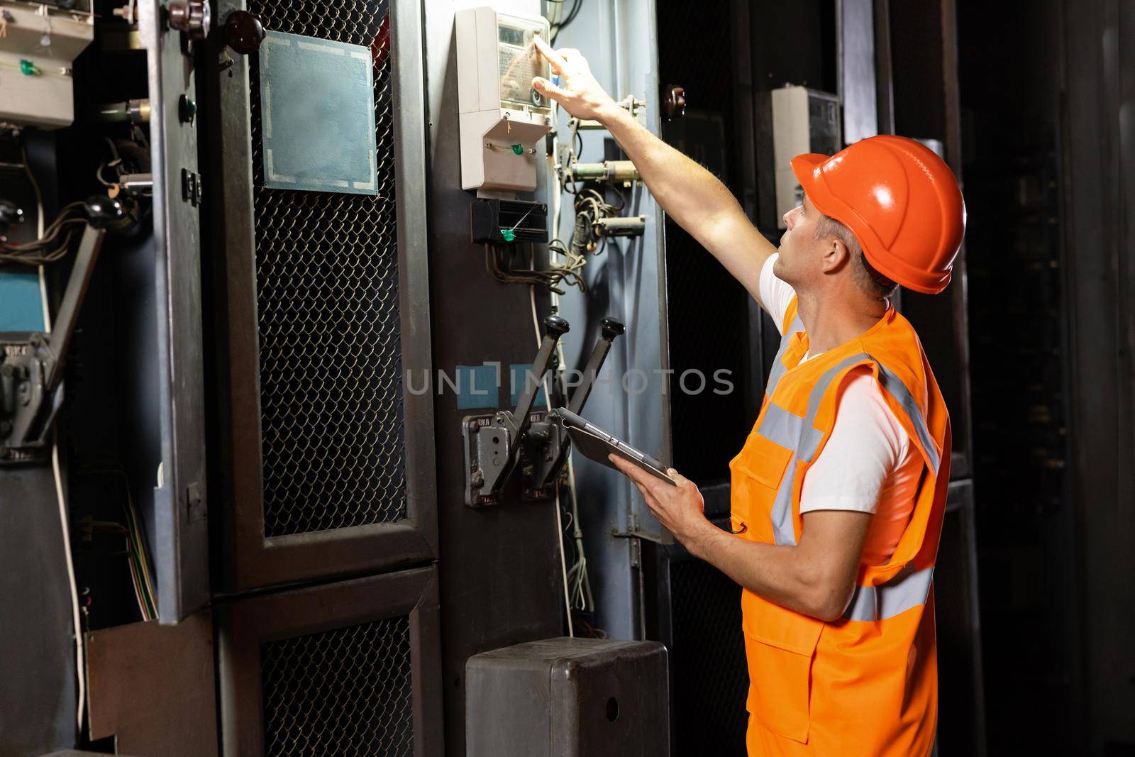 Engineer using digital tablet checking and inspecting at MDB panel working with electric switchboard to check range of voltage working in main distribution boards factory by uflypro