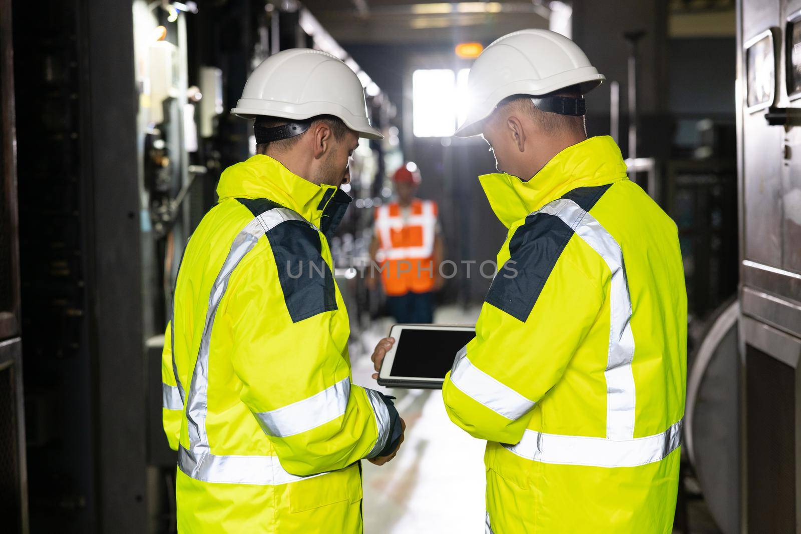 Two Heavy Industry Engineers Stand in Pipe Manufacturing Factory, Use Digital Tablet Computer, Have Discussion. Facility for Construction of Oil, Gas and Fuel Pipeline Transportation Products