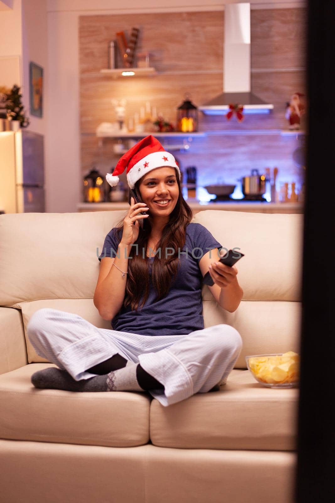 Adult person in sitting on couch talking at phone with friend celebrating christmas holiday by DCStudio