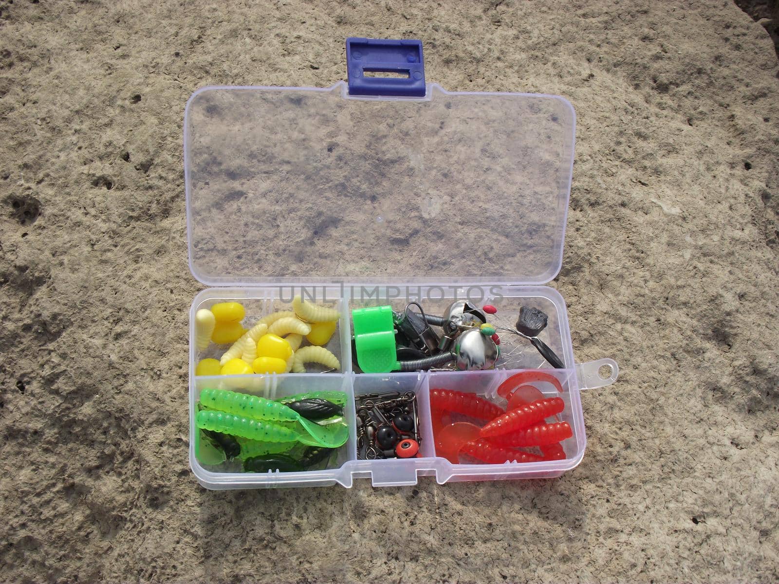 on the rocky shore, on one of the large stones, there are fishing tackle in a plastic box divided into sections