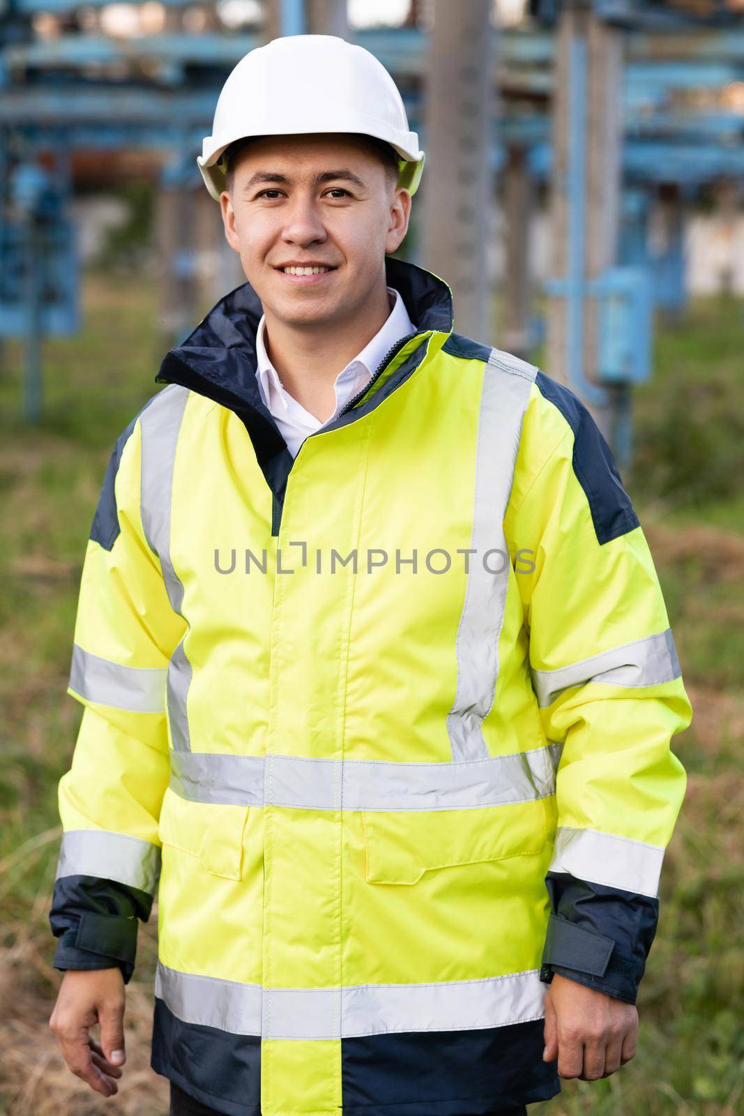 Portrait of asian ecology worker in hard hat standing at high voltage power station. Industrial people. Sustainable energy. Technology by uflypro