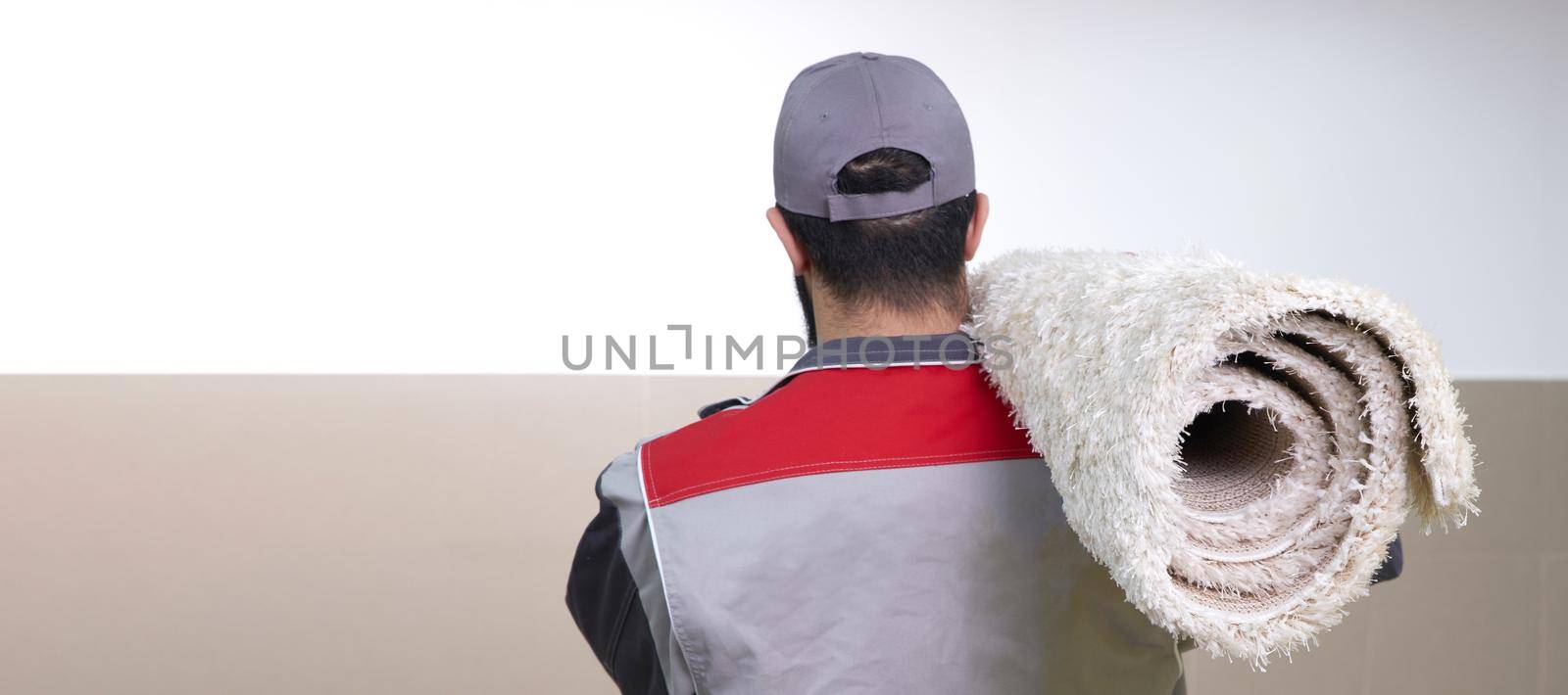 Rear view of man with a roll of carpet on a shoulder