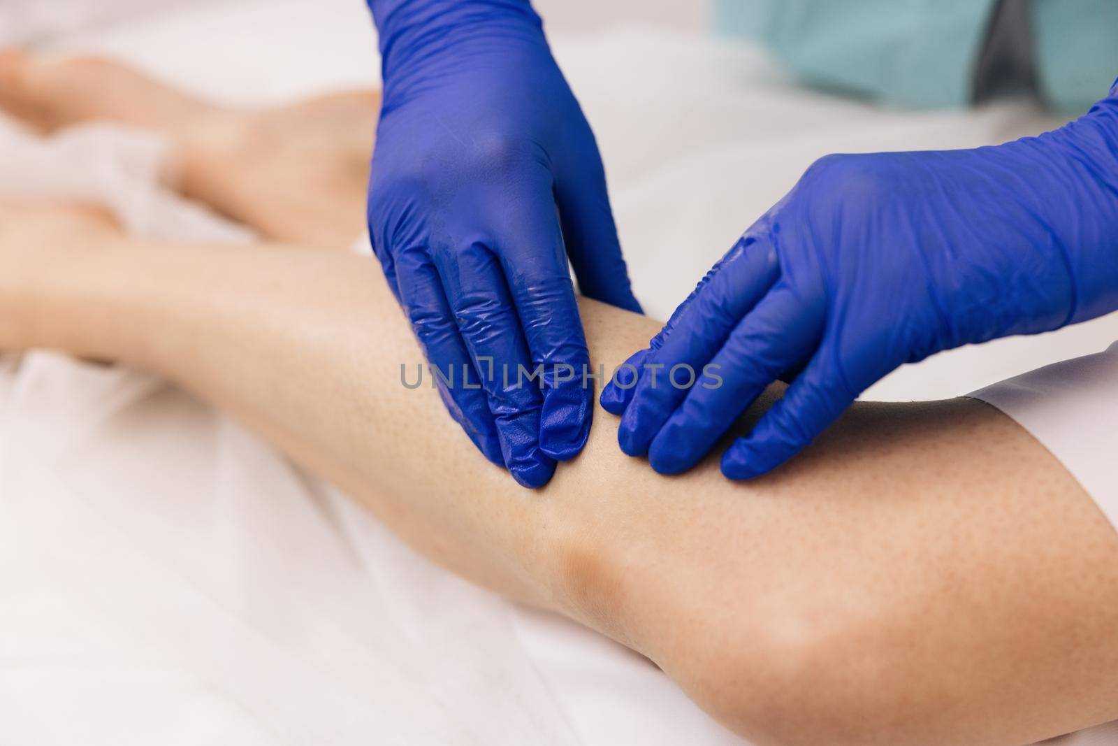 Healthcare medical insurance concept. Physiotherapist worker woman assisting physical medical exercise recovery after injuries. Doctor in gloves examining painful knee of female patient leg trauma by uflypro