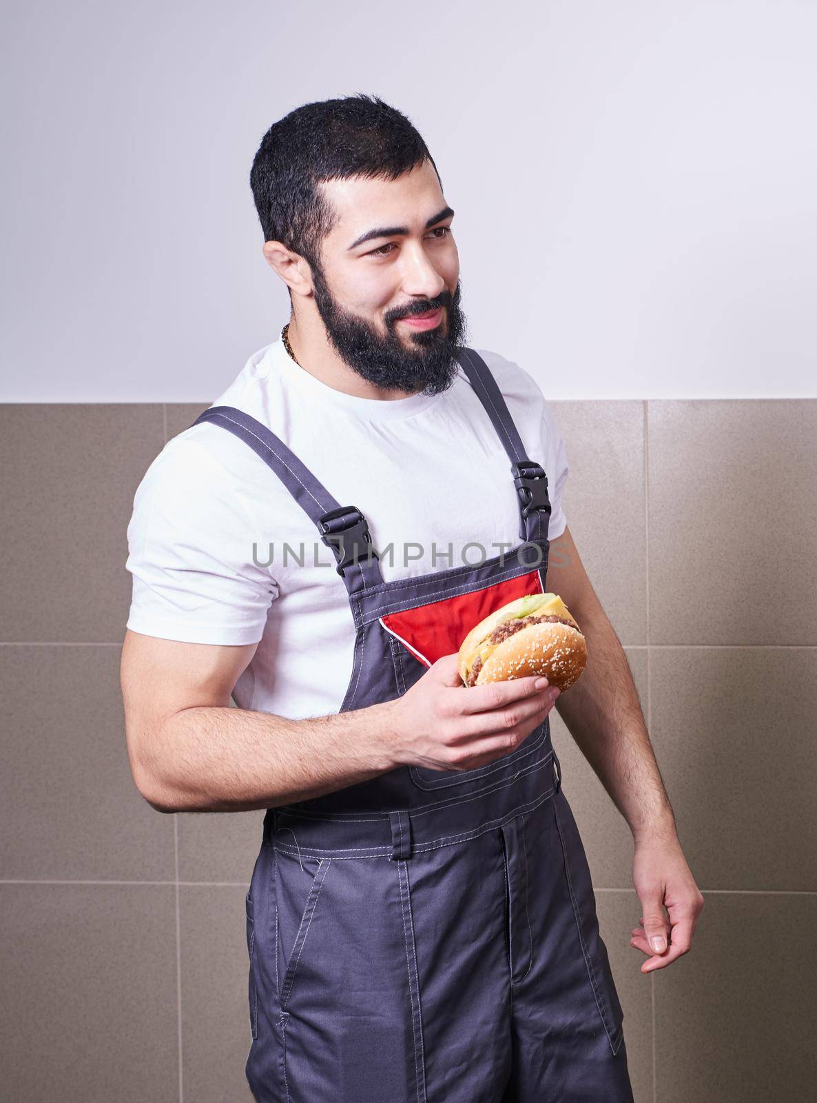 Worker wearing uniform eating burger during lunch break by Mariakray