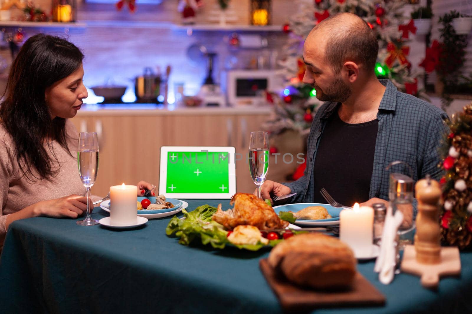 Happy family sitting at dining table in x-mas decorated kitchen by DCStudio