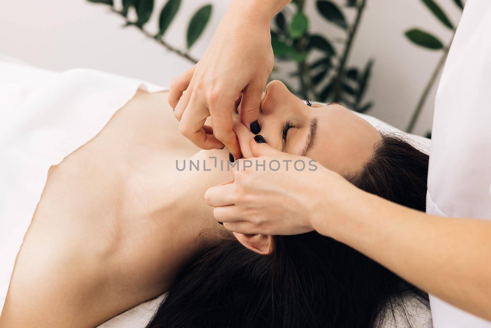 Face Massage in beauty spa salon. Female enjoying relaxing face massage in cosmetology spa centre. Body care, skin care, wellness, beauty treatment. Spa woman facial Massage.