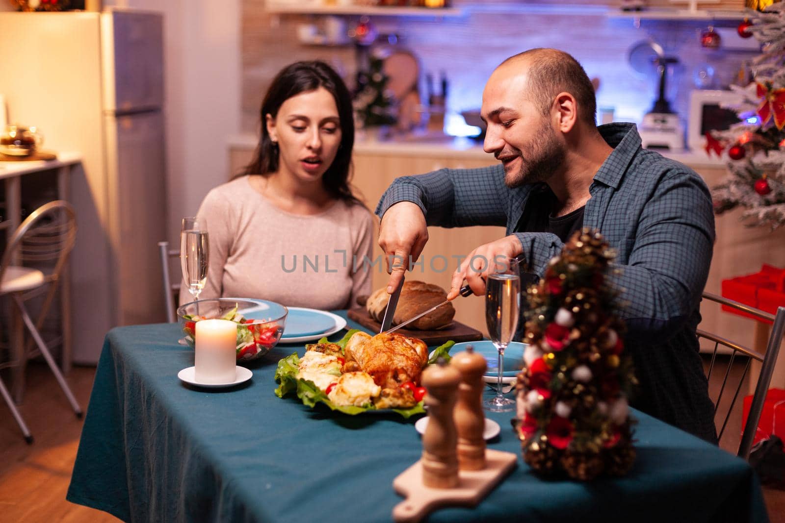 Happy family sitting at dining table in xmas decorated kitchen by DCStudio