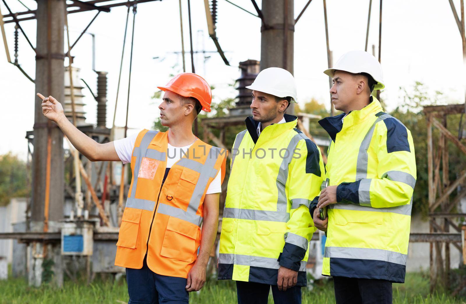 Electric industry, electrical energy production concept. Energy workers discuss work near power lines. Special workers planning a project at a power station.