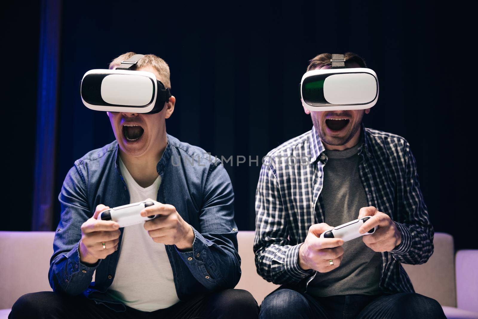 Young adults is playing video games at home. Emotional diverse gamers are holding joysticks and competition in intense video game on gaming console. They Plays with Wireless Controllers.