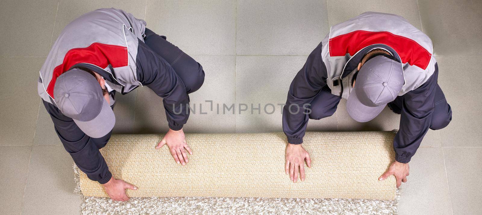 Male Worker Unrolling Carpet On Floor At Home