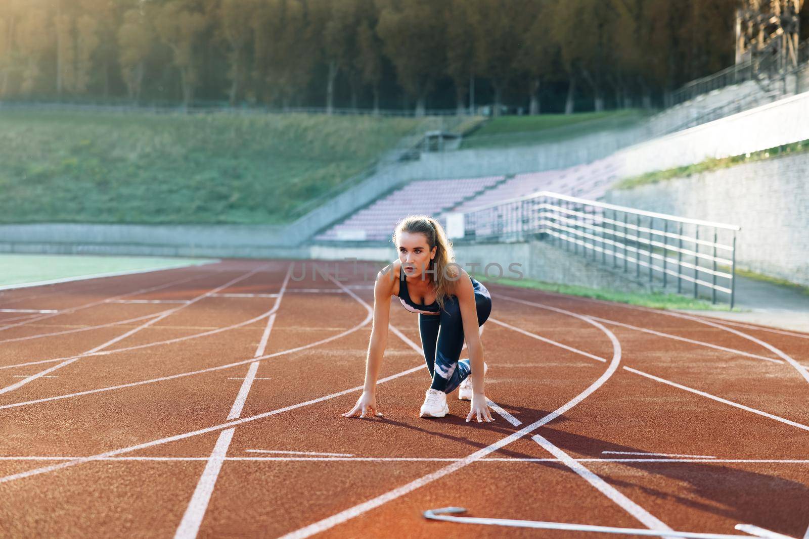 Female athlete starting her sprint on a running track. Runner taking off from the starting blocks on running track. Jogger activity. Female athlete. Sportswoman. Cardio exercises. Workout concept by uflypro