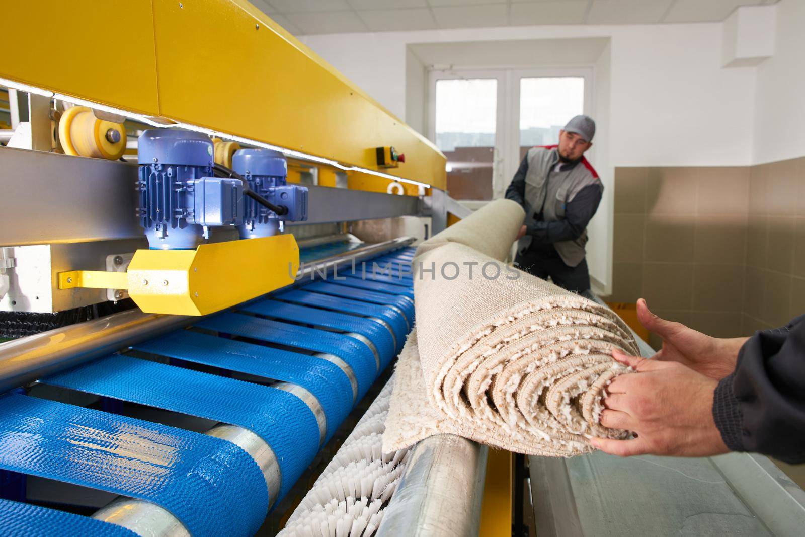 Laundry worker in the process of working on automatic machine for carpet washing in dry cleaning